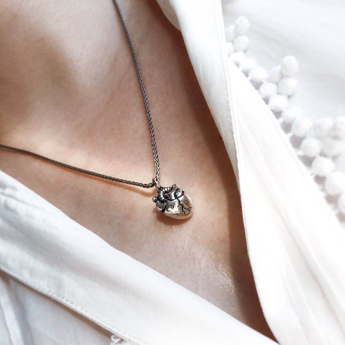 Sterling silver anatomical heart pendant worn on a foxtail chain. Symbolic jewelry with gothic and romantic aesthetics.