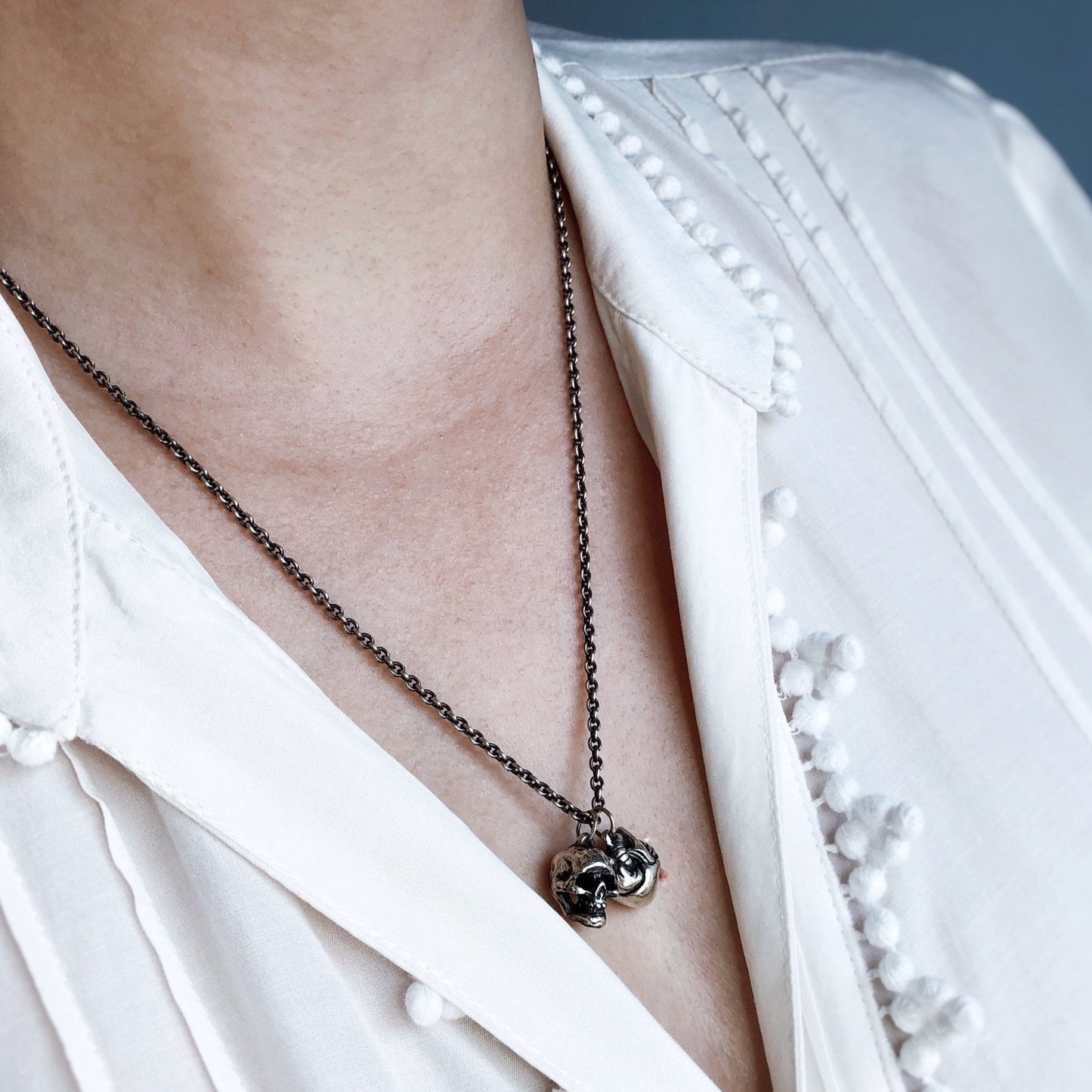 Oxidized sterling silver cable chain worn with pendant on neck, white shirt background