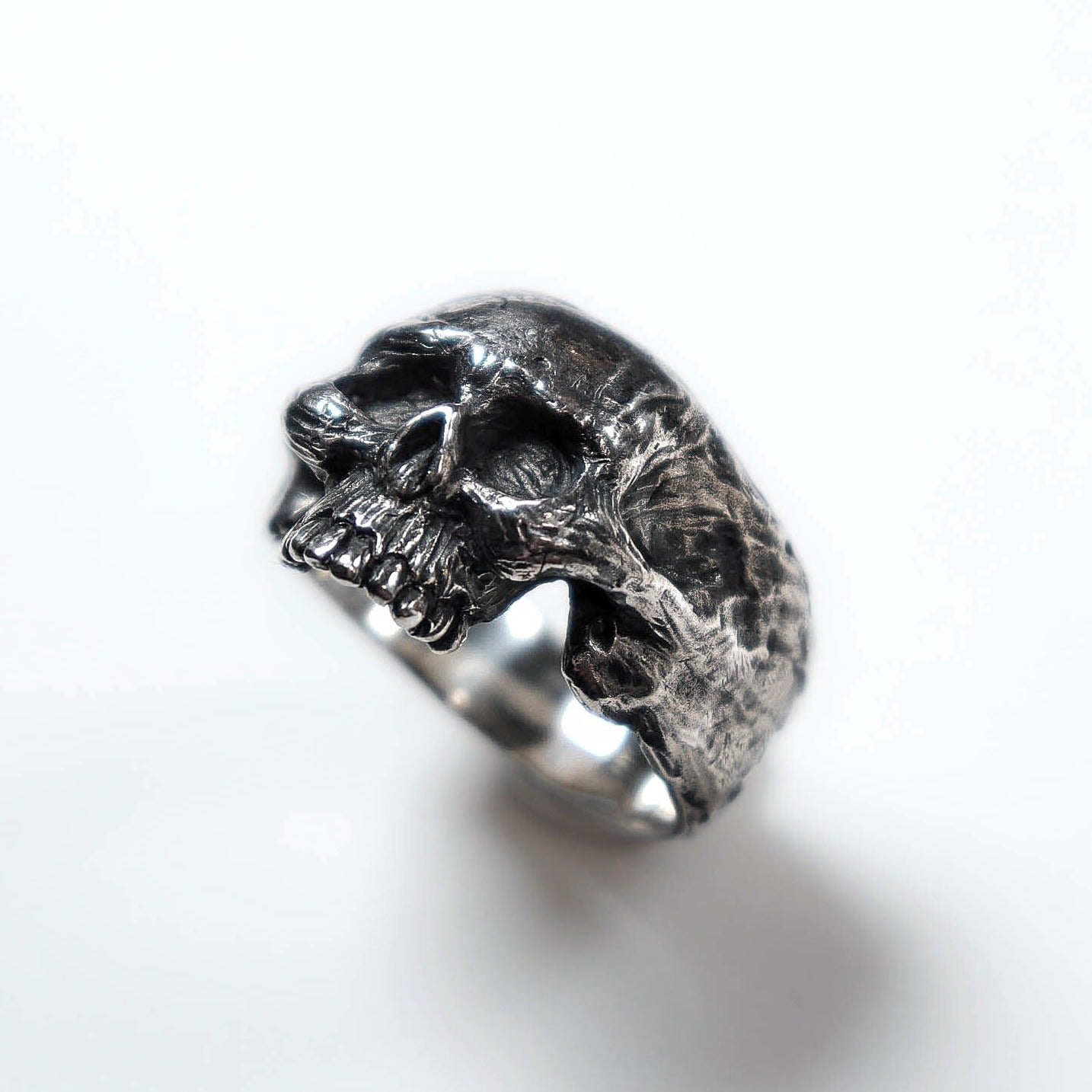 Oxidized sterling silver ring shaped as a human skull, sculptural and detailed, with textured handmade finish