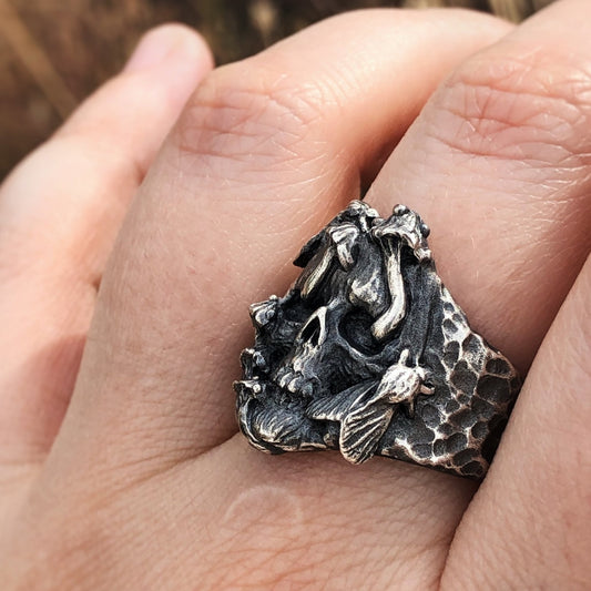 Statement silver ring with sculpted skull, moths, and mushrooms, worn on hand — fantasy-inspired, symbolic gothic jewelry with dark nature elements.