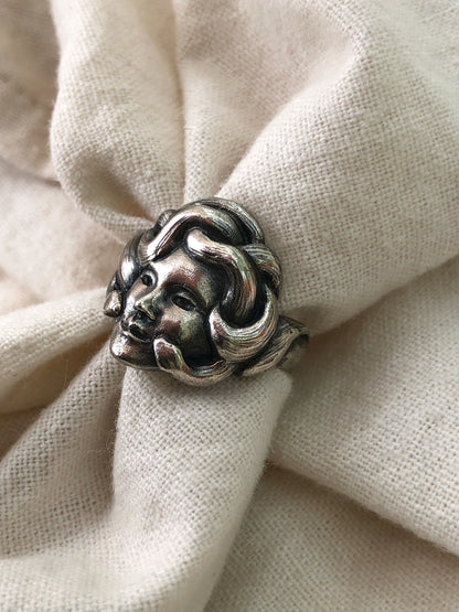 Sterling silver Medusa ring with sculpted serpent crown, mythology-inspired jewelry photographed on soft neutral fabric background
